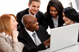 group of business people gathered around a laptop